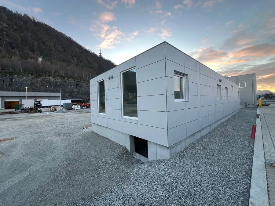 Lyst grått TEK17-modulbygg med store vinduer på betongfundament ved havna i Ålesund, levert til PTG Tempra
