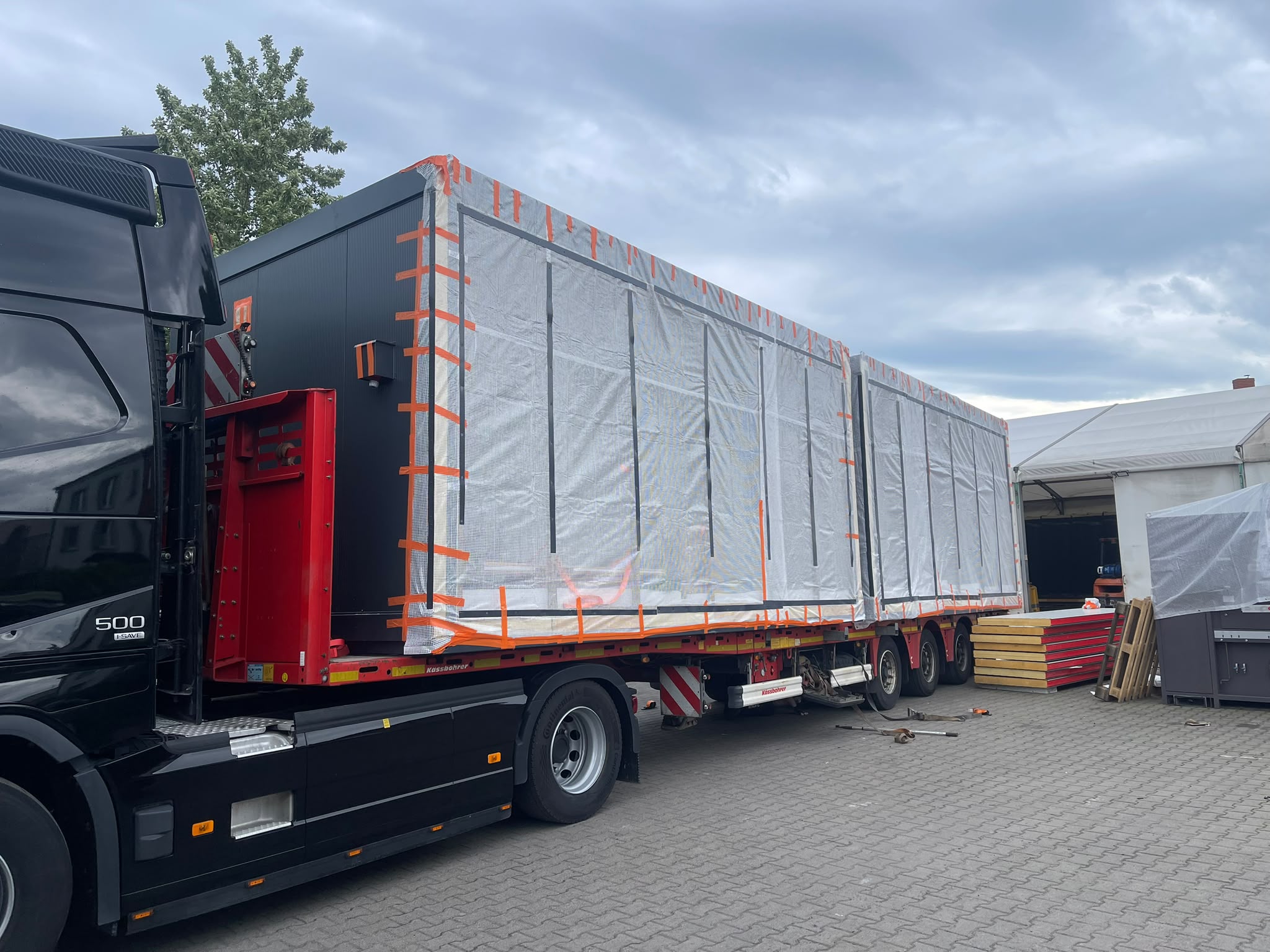 To moduler pakket inn i beskyttelsesplast og sikret på semitrailer, klare for transport